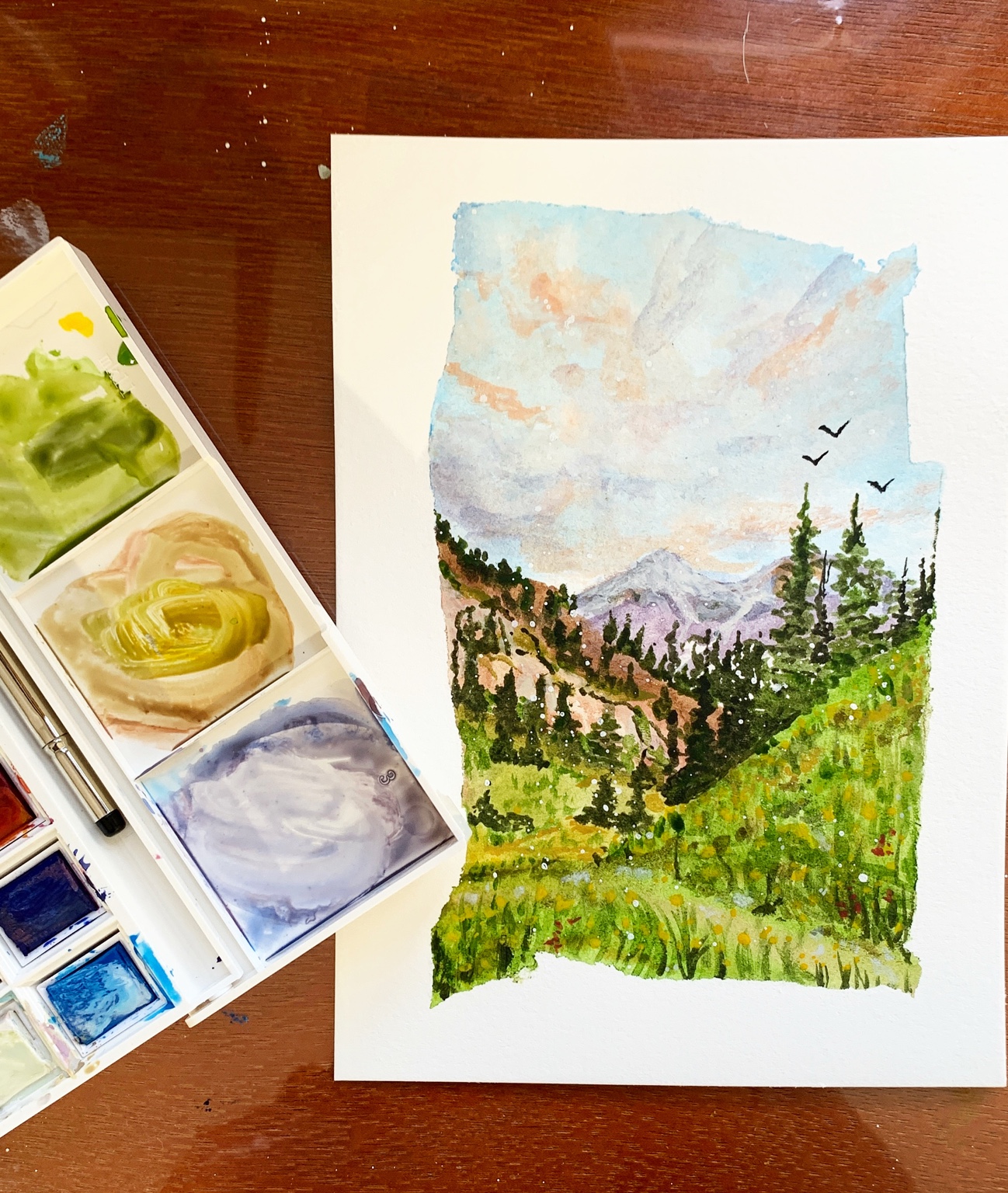 A watercolor mountain landscape on Christina's paint table